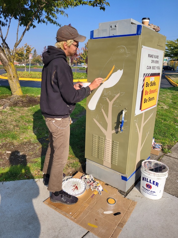 Madison painting an electrical box wearing a mask.
