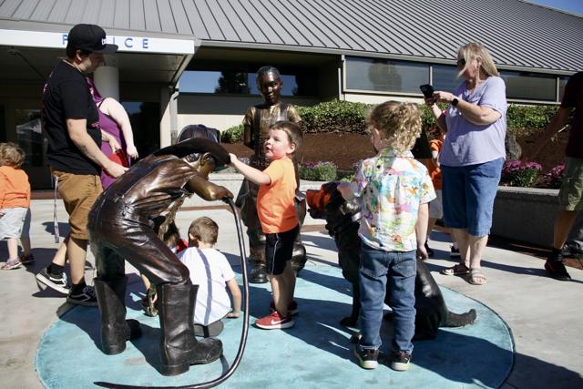 Kids admiring the boy statue drinking water.