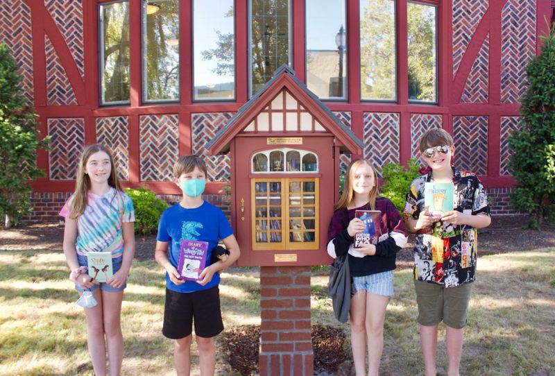 Children with books next to the little library