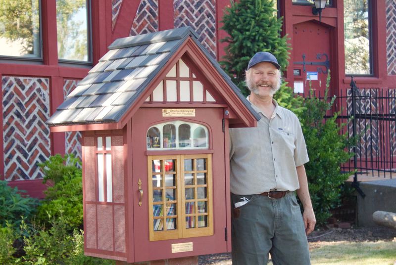 Creator Mark Klobas standing next to little library.