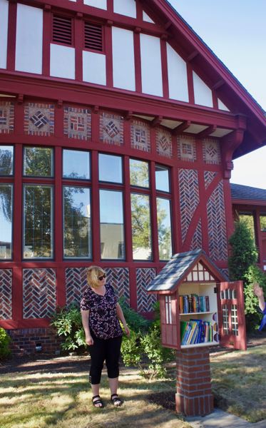 Woman looking at open little library.